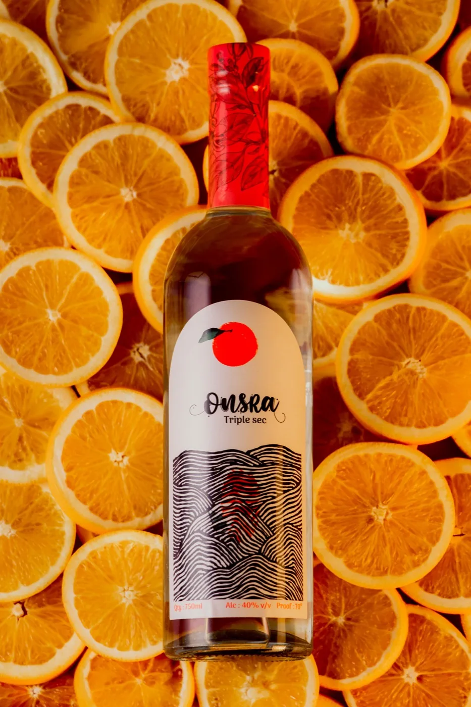 A bottle of Onsra Triple Sec lying on sliced oranges