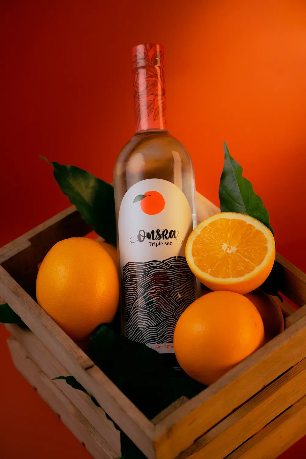 A bottle of Onsra Triple Sec in a wooden crate with oranges
