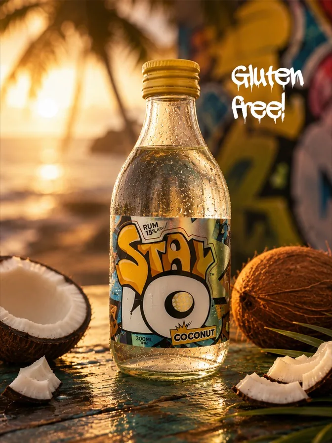 A bottle of StayLo Coconut with coconuts on a beach at sunset